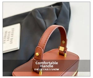 Close-up of brown leather handle with gold hardware and fine stitching on a box bag