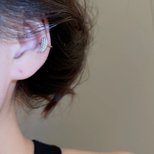 Macro shot of silver wing-shaped ear cuff with pave-set zircons on model's ear