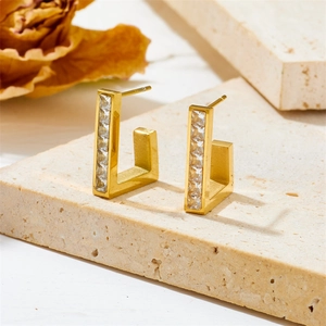 Minimalist gold G-shaped earrings with square clear stones on a textured stone base