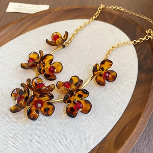 Macro detail of amber leopard print flower necklace with red center on gold metal chain
