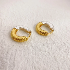 Macro detail of two-tone gold and silver earrings featuring unique molten lava texture