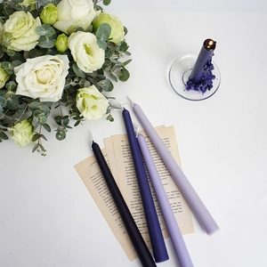 Elegant purple tapered candles set with white roses and vintage book pages detail