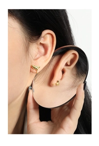 Close-up of irregular liquid metal gold stud earrings with a glossy mirror finish on model