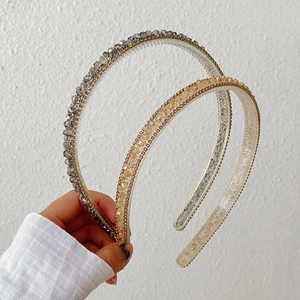 Detailed view of three shimmering crystal beaded headbands in grey, gold, and clear colors