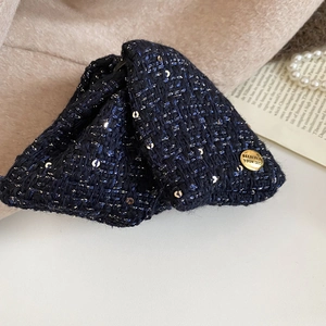 Detail of navy blue tweed bow hair claw with gold engraved button and silver sequins