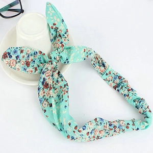 Floral print headband with rabbit ear bow on a clean white background