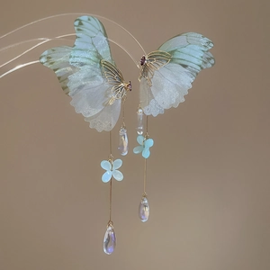 Detail of elegant butterfly tassel earrings with translucent wings and small blue flower