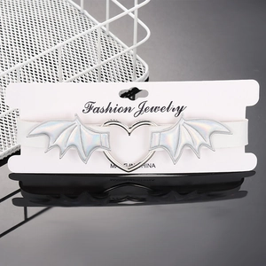 Close-up of white gothic choker featuring a silver heart ring and holographic bat wings