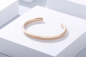 Macro detail of rose gold open cuff bracelet with One Life One Love engraving