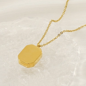 Minimalist gold stainless steel necklace with octagonal rectangle pendant on glass tray