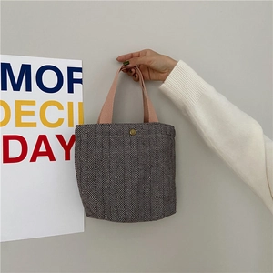 Detail of herringbone canvas handbag with pink strap and golden button closure