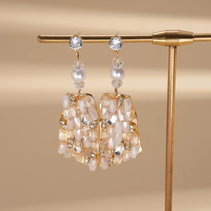 Detailed shot of bohemian gold square earrings with white seed beads and shiny rhinestones