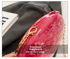 Detailed close-up of pink marble acrylic evening bag with gold metal hardware and chain
