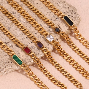 Detail of 18K gold Cuban chain with multicolor zircons and agate on stone texture