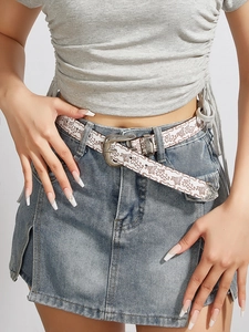 Detail of vintage silver buckle on brown floral pattern belt over blue denim skirt