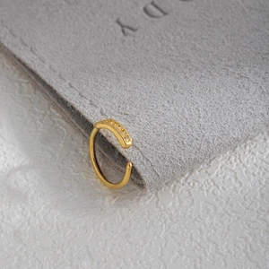 Close-up of a gold leaf nose ring with sparkling cubic zirconia on gray velvet