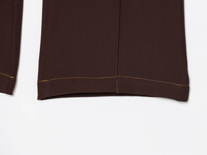 Detail of dark brown flare trousers showing precision orange stitching and twill fabric