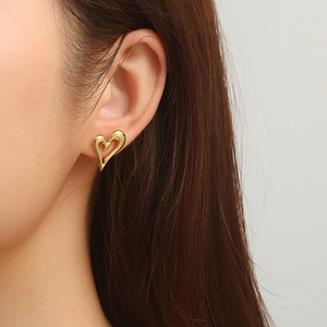 Close-up of a gold heart-shaped stainless steel earring worn on a model's ear