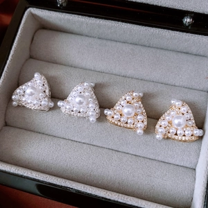 Macro shot of triangle stud earrings with inlaid pearls and zircon in a velvet jewelry box