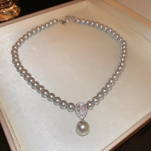 Detail of gray pearl necklace with zircon teardrop pendant in beige jewelry box