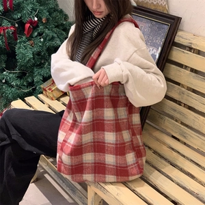 Detail view of red and white checkered plush tote bag in a cozy winter holiday scene
