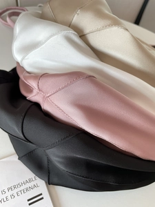 Detailed view of champagne, white, pink and black satin fabric with silky smooth texture