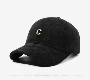 Close-up of black herringbone wool baseball cap with a 3D gold metal C letter logo
