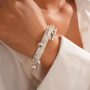 Gros plan de clochettes en argent poli sur un bracelet tissé texturé pour femme