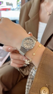 Close-up of a ladies' silver watch with a rhinestone bezel and grey dial on wrist