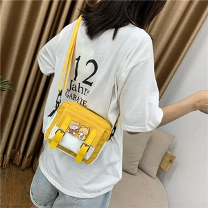 Detail view of yellow and white canvas crossbody bag with cartoon bear and girl prints