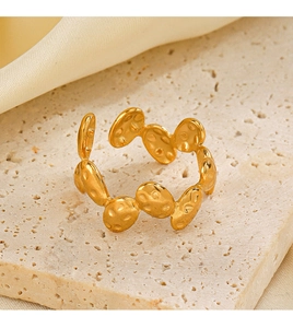 Detailed close-up of golden oval ring with irregular hammered texture on beige stone