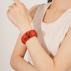Detail of red marble texture acrylic geometric wide bangle bracelet on female wrist