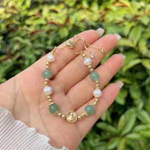Detail of 18k gold beads, pearls, and green gemstones with Virgin Mary charm