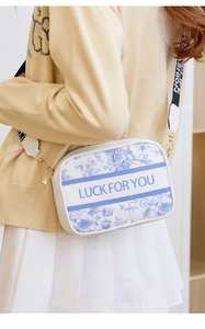 Detail of blue and white vintage floral crossbody bag with Luck For You printed logo