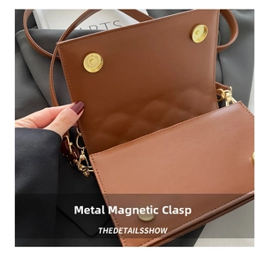 Detail shot of the gold magnetic hardware buckles on a brown leather crossbody bag