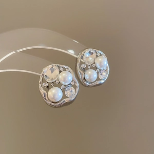 Macro shot of silver stud earrings with irregular pearls and sparkling rhinestones