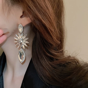 Macro shot of long silver flower drop earrings with sparkling rhinestones on ear