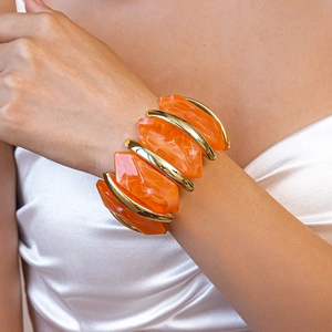 Détail du bracelet en résine orange marbrée avec bords dorés sur le poignet d'un modèle