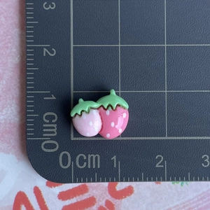 Macro shot of 2cm mini resin strawberry charms on a scale ruler for DIY jewelry crafts