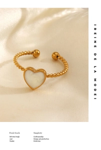 Close-up of golden twist rope ring with white marble heart inlay on beige silk