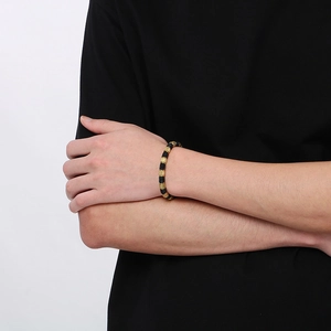 Detailed close-up of men's black and gold beaded bracelet on a male model's wrist