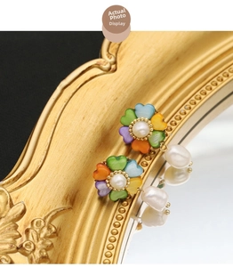 Detailed macro view of vintage gold flower earrings with pearls on a reflective mirror