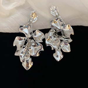 Macro detail of silver acrylic petal tassel earrings on black and white fabric