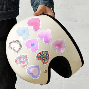 Close-up of heart-shaped stickers in watercolor and floral patterns on a cream helmet