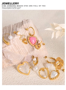 Detail of vintage gold heart earrings with pearls and pink enamel on a stone backdrop