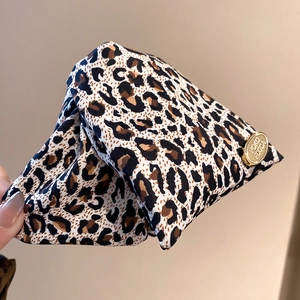 Detailed close-up of leopard print fabric texture and a polished gold POKO metal tag