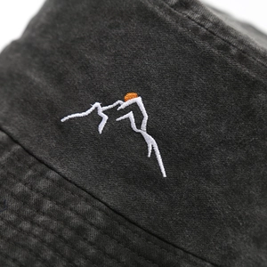 Distressed dark gray bucket hat featuring colorful mountain sun embroidery in a side view
