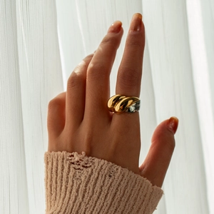 Close-up of two-tone croissant ring worn by a model against soft natural lighting