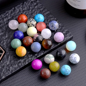 Macro shot of 16mm assorted natural crystal spheres on a textured black stone plate