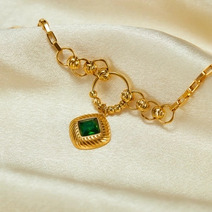 French vintage style gold necklace with square emerald zircon on white silk background